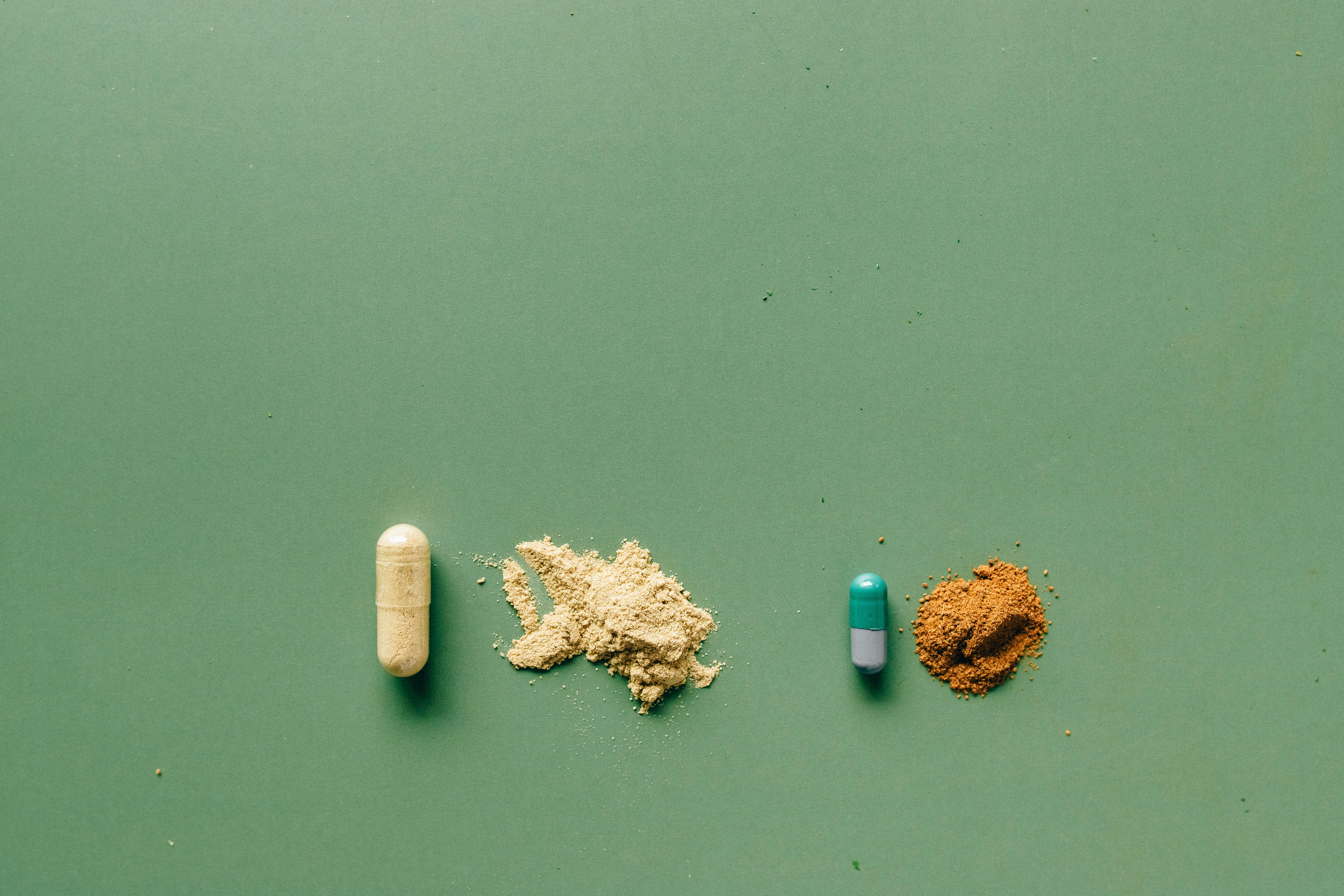 Variety of capsules and powders arranged on a green backdrop