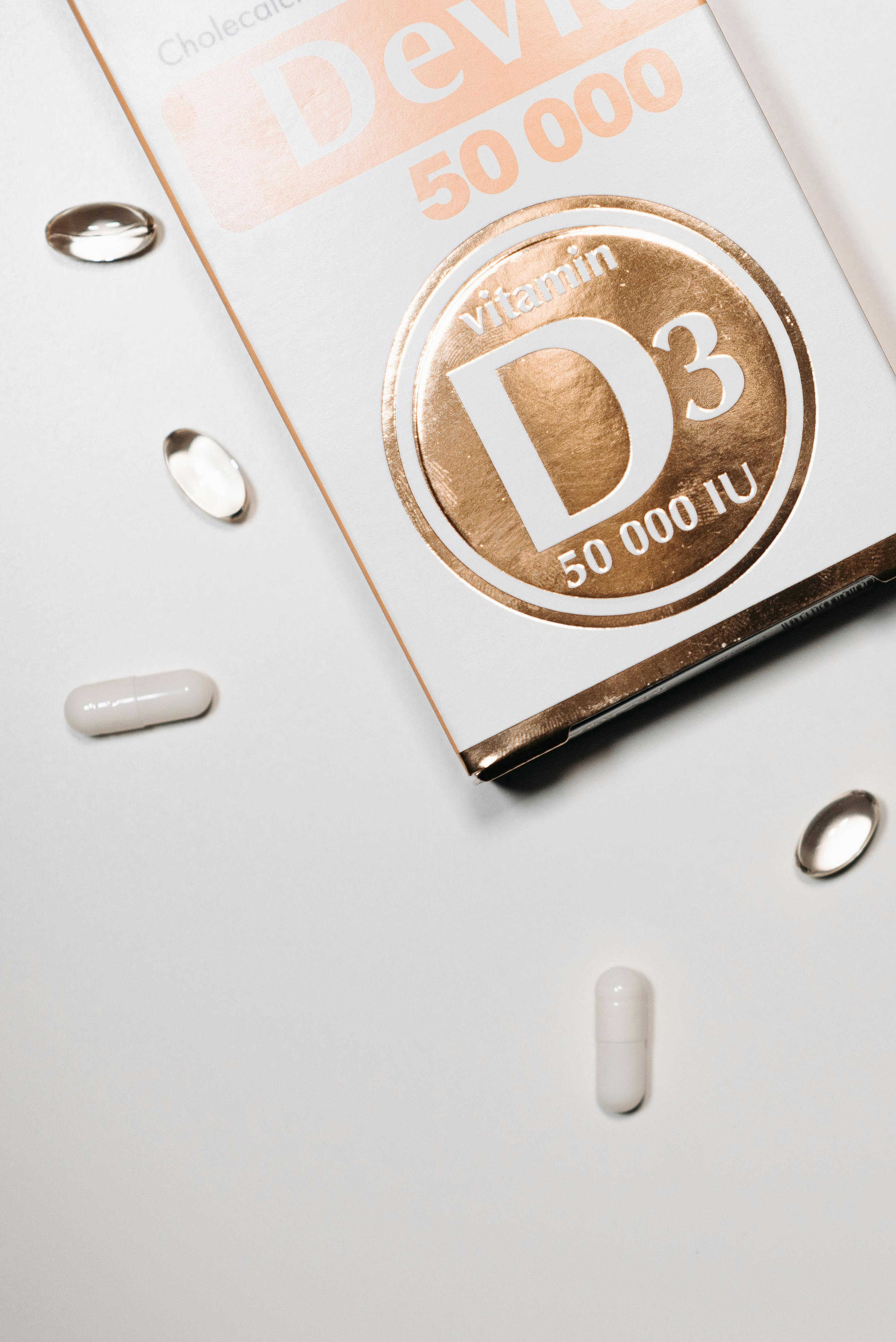 Close-up of vitamin D3 capsules and box on a clean white surface
