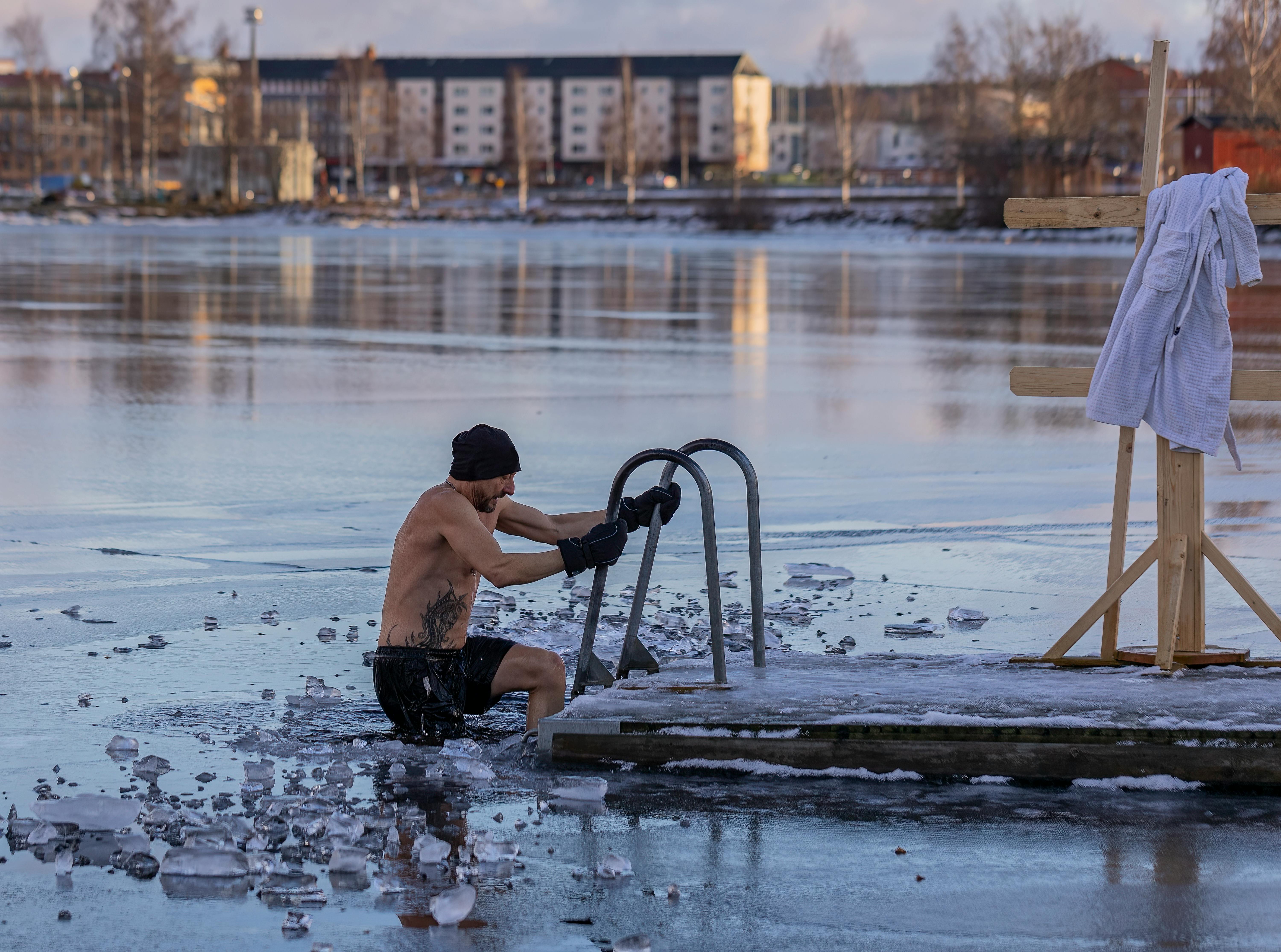 Shirtless man standing in a freezing lake near Ludvika, Sweden, surrounded by snow and ice during winter cold water immersion