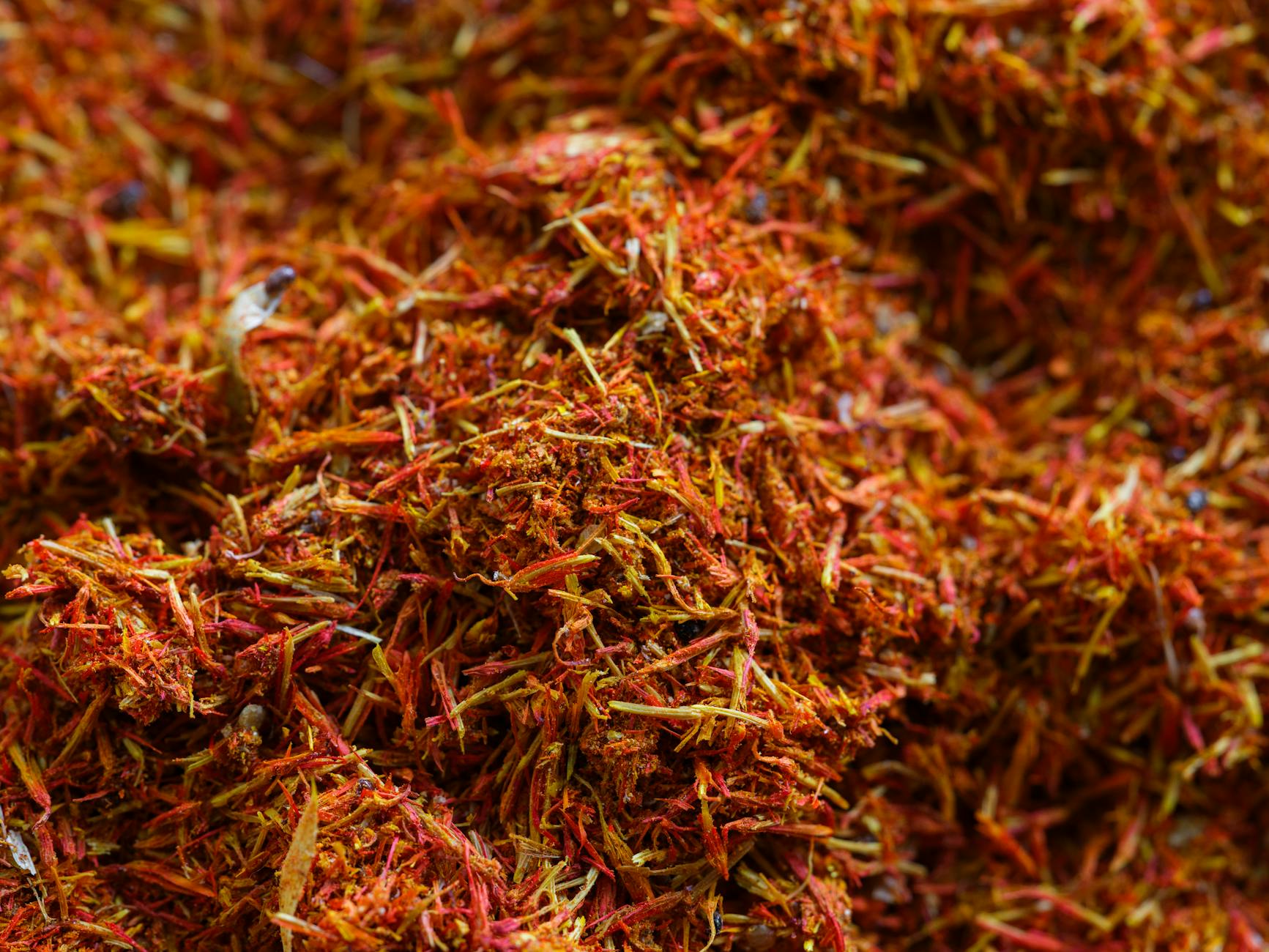 Close-up of vibrant saffron threads on a dark surface, the red stigmas arranged in loose clusters