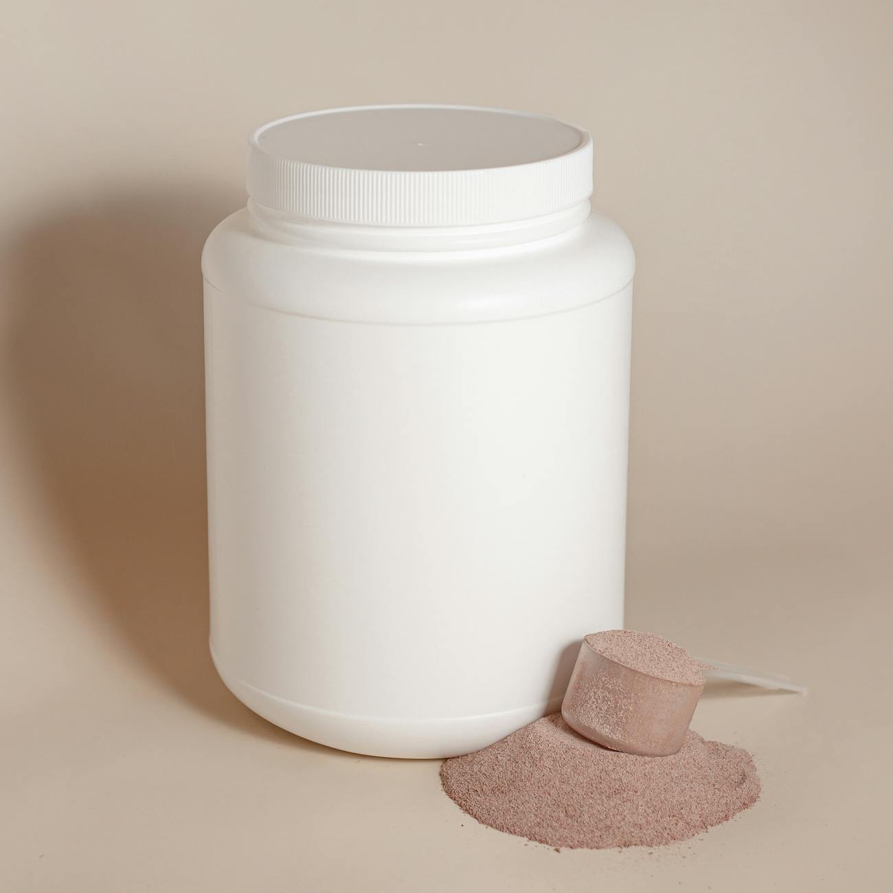 Unlabelled white container and scoop beside creatine powder.